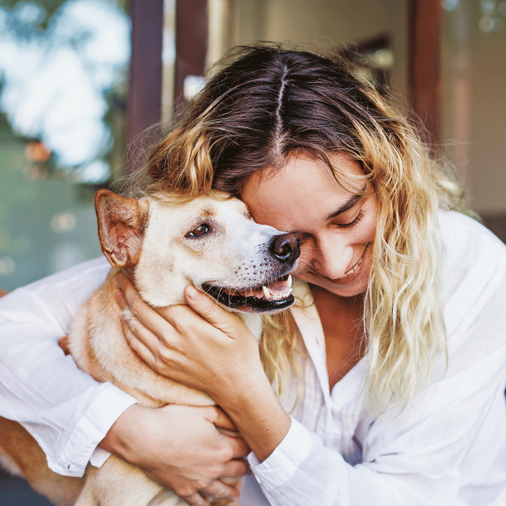 A woman lovingly hugs her dog